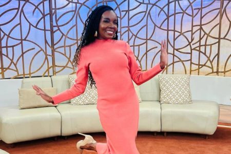 Foto colorida de Thelma Assis nos bastidores do Encontro usando vestido rosa e sorrindo - Metrópoles