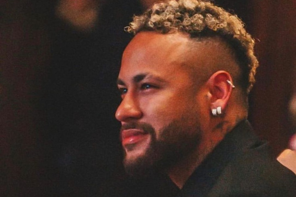 Foto colorida de Neymar. Ele está de roupa preta e usa brincos - Metrópoles