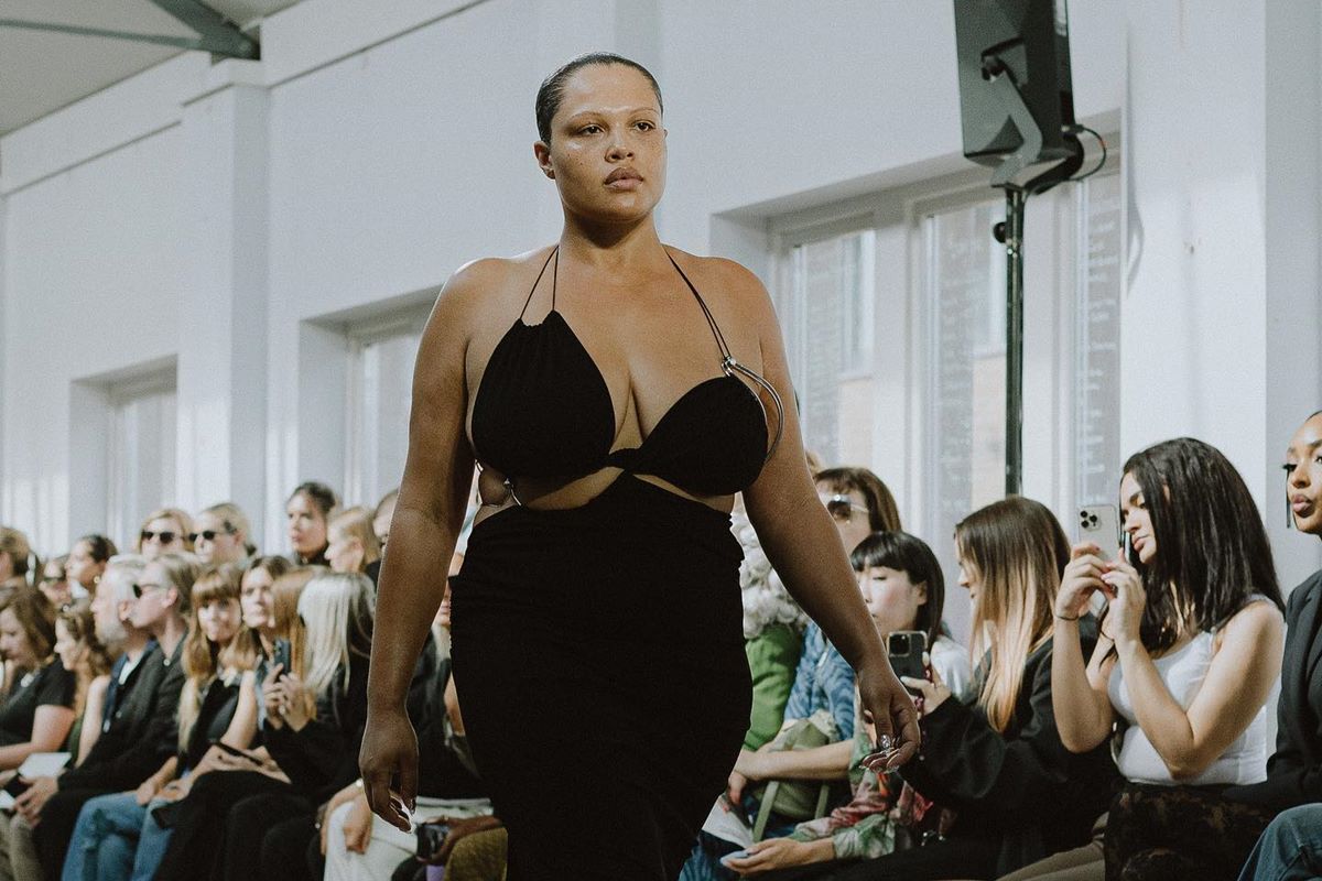 Na passarela de moda, modelo usa vestido preto com recortes e alças finas - Metrópoles