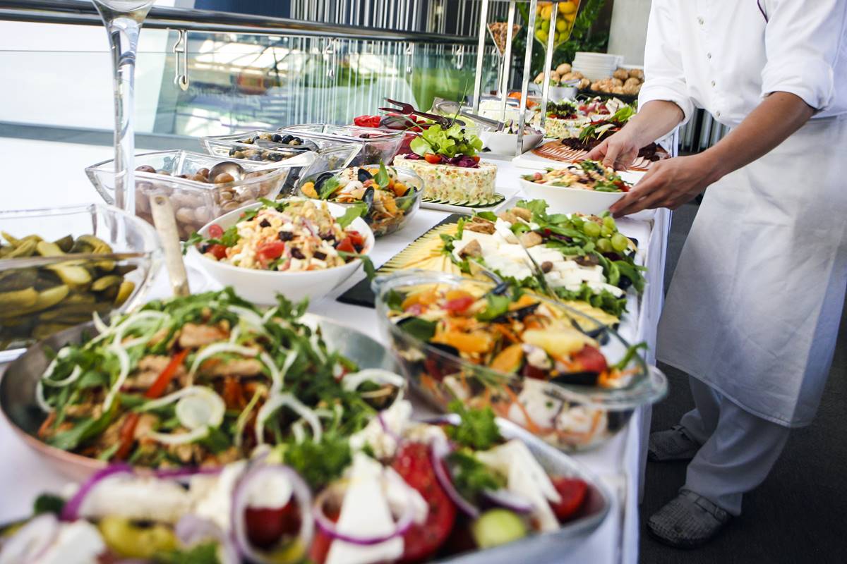 Foto colorida de buffet de hotel. A longa mesa, forrada com um pano branco, dispõe de diversos pratos - Metrópoles