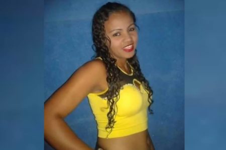 Mulher negra, de cabelos escuros cacheados veste camisa amarela