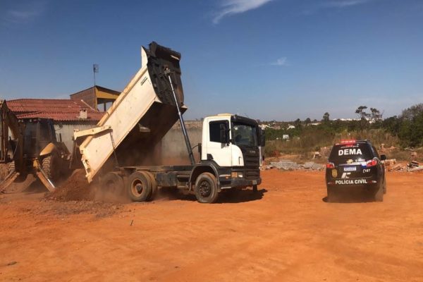 caminhão despejando terra ao lado de viatura da pcdf