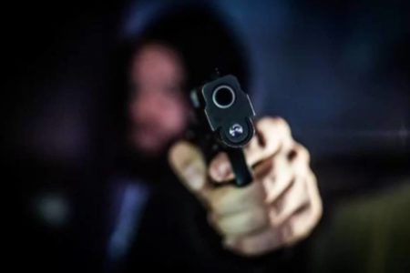 homem com capuz apontando arma