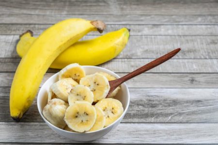 Imagem colorida de uma vasilha com banana ao lado de duas banana inteiras - Metrópoles