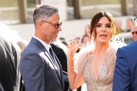 Foto colorida de Bryan Randall e Sandra Bullock em tapete vermelho - Metrópoles