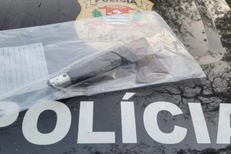 Imagem colorida mostra uma faca com cabo preto embalada em envelope plástico, em cima de capô de carro da Polícia Civil - Metrópoles