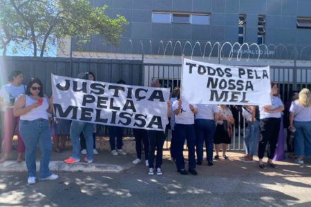 Grupo de pessoas em frente ao Tribunal do Júri de Sobradinho pedindo por Justiça. Seguram cartazes pedindo Justiça pela Melissa e Todos pela Nossa Mel