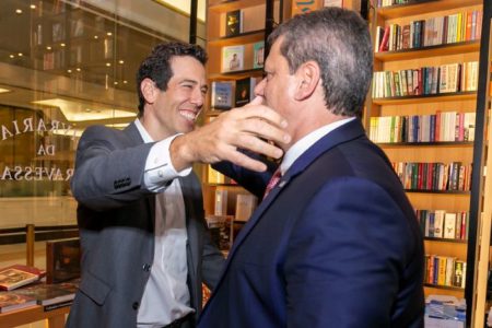 Imagem colorida mostra secretário da Educação Renato Feder, um homem branco de cabelos pretos vestindo uma camisa branca e um terno cinza, abraçando o governador Tarcísio de Freitas, um homem branco com cabelos grisalhos vestindo um terno azul-marinho, em São Paulo - Metrópoles