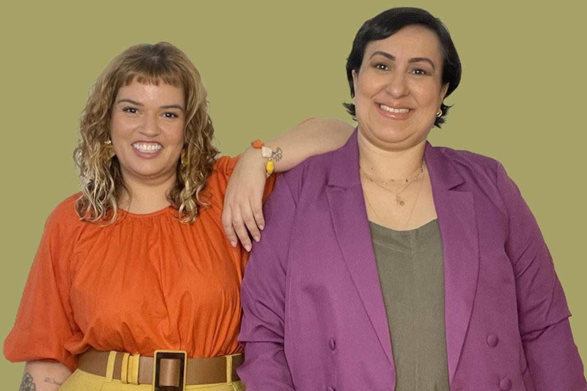 Duas mulheres posando para foto. Uma está apoiando o braço no ombro da outra. A dupla está sorrindo para o clique - Metrópoles