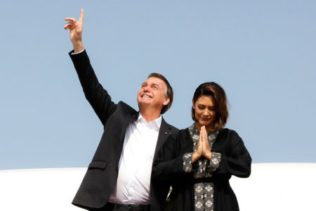 O então presidente, Jair Bolsonaro, aponta para o céu, enquanto a então primeira-dama, Michelle Bolsonaro, faz gesto de oração