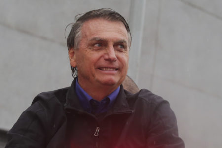 Jair Bolsonaro, vestido com uma camisa azul e uma blusa preta, sorri durante comício em Santos no Litoral de São Paulo -Metrópoles
