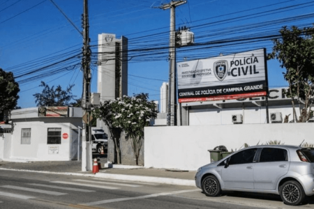 Imagem colorida mostra a fachada da Central de Polícia Civil de Campina Grande. Os muros são brancos e há uma placa da Polícia Civil na parte de cima da casa - Metrópoles