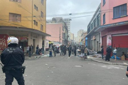 Foto colorida mostra usuários de drogas da Cracolândia concentrados sob escolta da GCM