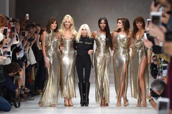 Na imagem com cor, Donatella Versace posa ao lado de cinco super modelos no final do desfile - Metrópoles