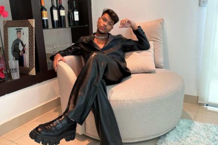 Foto colorida de Jessé Aguiar usando roupa toda preta e sentado em um sofá - Metrópoles