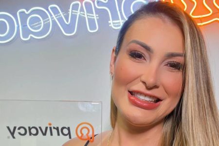 Foto colorida de Andressa Urach sorrindo e segurando placa do Privacy - Metrópoles