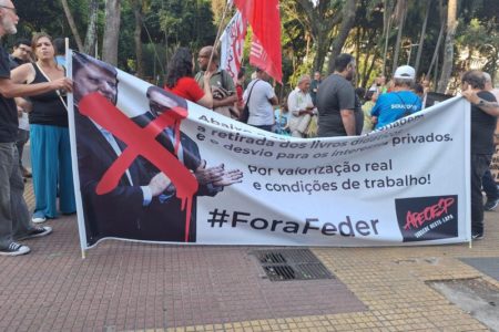 Imagem colorida mostra professores segurando uma faixa branca com as fotos do governador Tarcísio de Freitas e do secretário de Educação, Renato Feder, com um X vermelho em cima deles. No texto da faixa, está a inscrição #foraFeder - Metrópoles