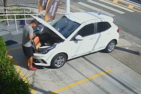 Em foto colorida outro criminoso abre capô de carro - Metrópoles