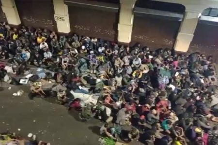 foto colorida feita do alto de um prédio na Cracolândia mostra usuários de drogas reunidos e sentados em uma rua da região durante a madrugada