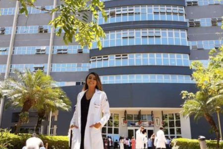 Imagem colorida de Thalitta Fernandes. É uma foto frontal da médica, com a faculdade aos fundos - Metrópoles