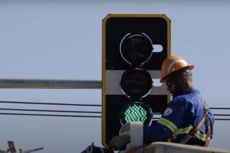 foto colorida de funcionário instalando semáforo inteligente em SP