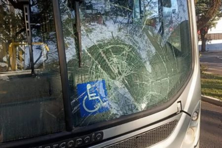 Imagem colorida de ônibus com vidro quebrado pelo impacto - Metrópoles