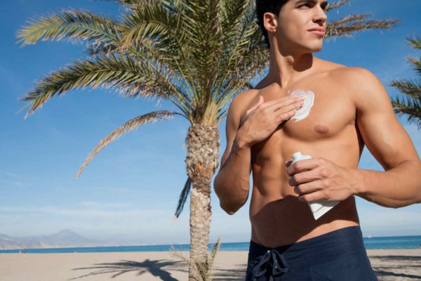 Foto mostra homem sem camisa aplicando o filtro solar