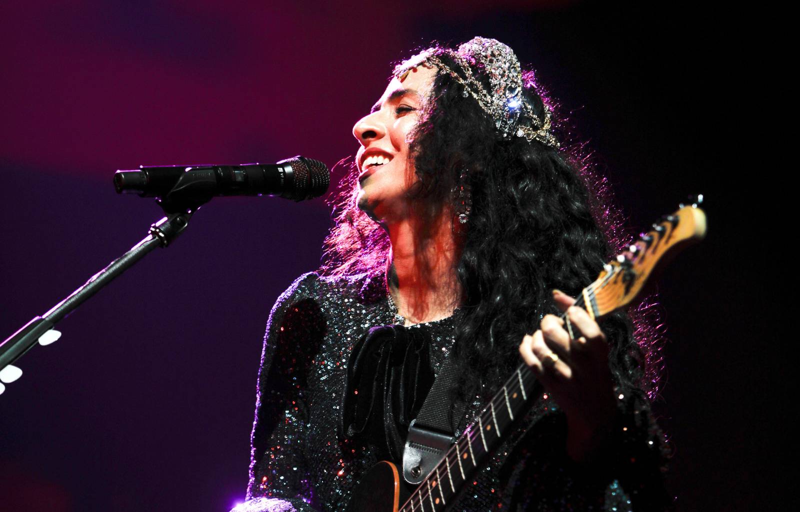 Fotografia colorida de Marisa Monte tocando um violão na turnê Portas