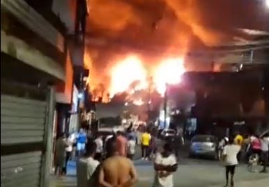 Imagem colorida mostra incêndio em uma indústria química na zona norte de SP. Moradores da região observam de longe as labaredas - Metrópoles