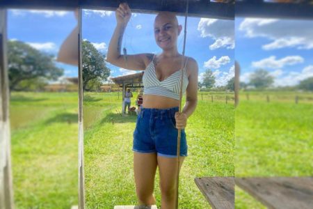 Mulher com top e short jeans segura vara de pescar