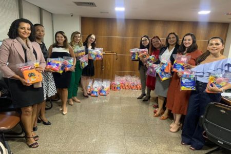 Imagem colorida mostra mulheres segurando kits de higiene básica