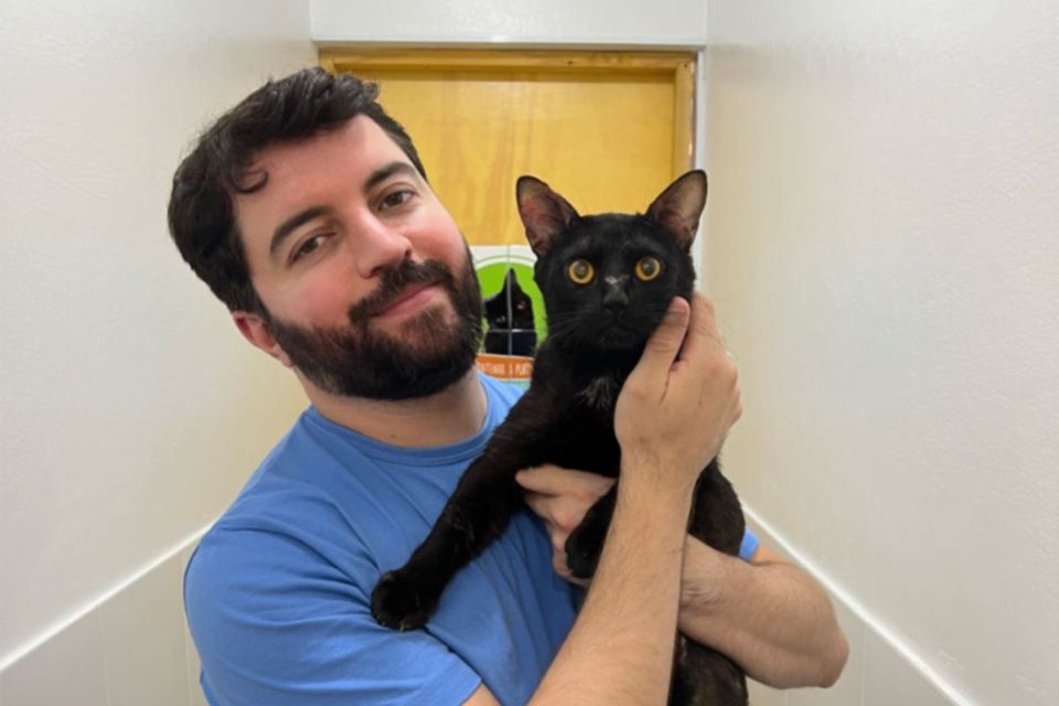 Foto colorida de homem segurando um gato - Metrópoles