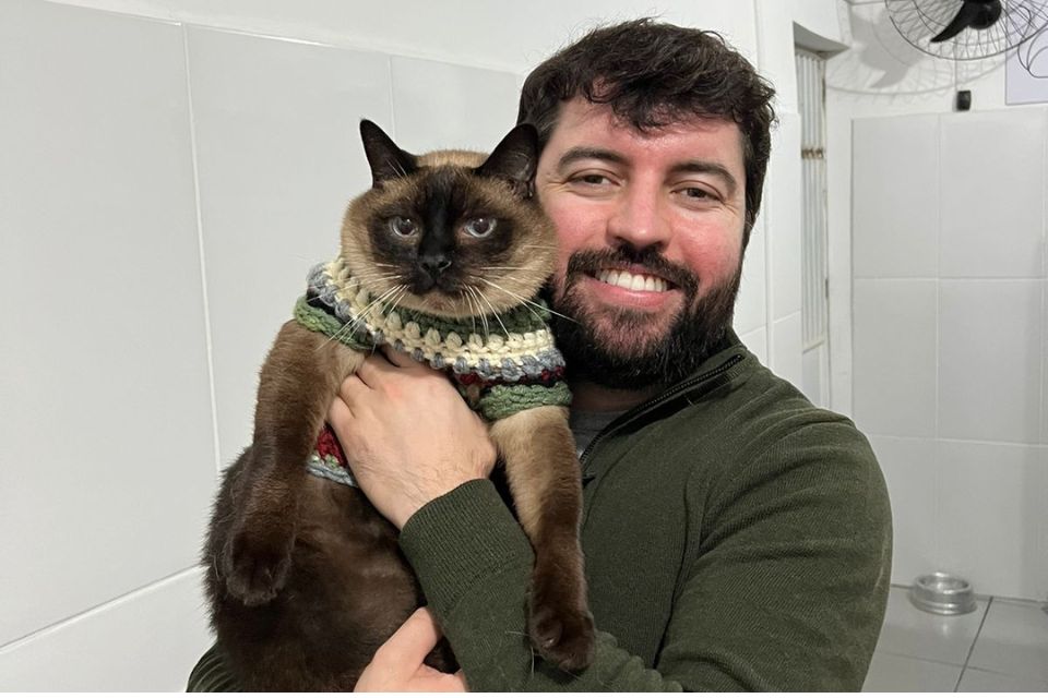 Foto colorida de homem segurando um gato - Metrópoles