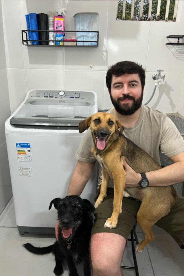 Foto colorida de homem e um cachorro no colo - Metrópoles