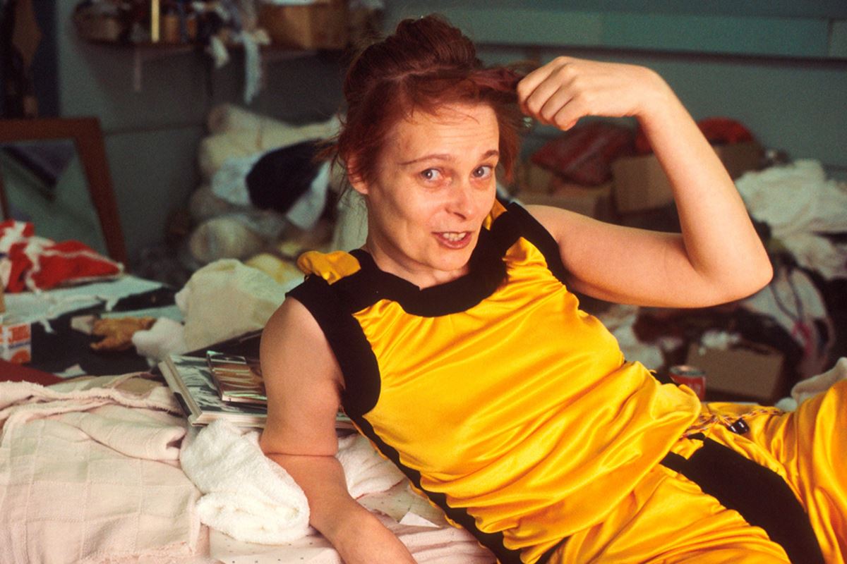 Vivienne Westwood usando roupa amarela em ateliê de moda. Posição deitada e mexendo no cabelo - Metrópoles