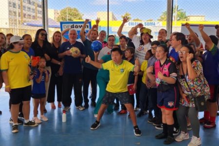 Imagem colorida de jovens e adusltos com síndrome de Down em quadra de futsal