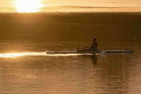 Uma pessoa rema no Lago Paranoá iluminada pelo sol calor