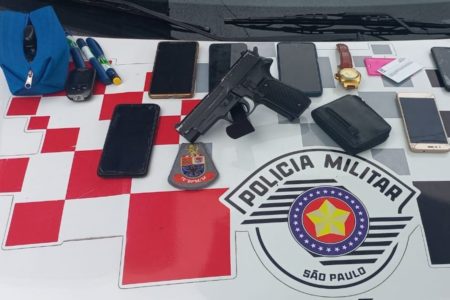 Imagem mostra celulares, relógios e arma falsa sobre símbolo da PM - Metrópoles