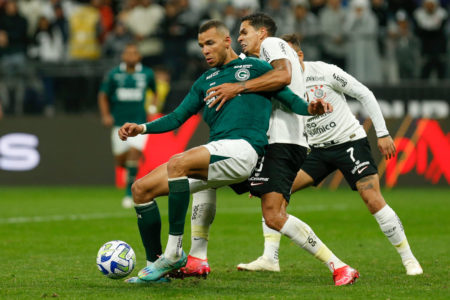 dois jogadores de futebol do corinthians e do goias disputando a bola