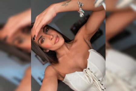 Mulher branca em selfie roupa branca modelo "tomara que caia" com tatuagem no pulso