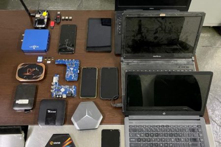 Imagem colorida mostra três notebooks, alguns aparelhos celulares e placas de computadores apreendidos durante operação policial contra a pedofilia - Metrópoles