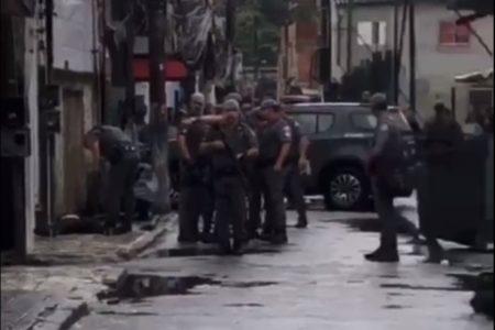 Imagem colorida mostra policiais reunidos em viela no Guarujá