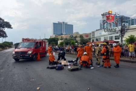 ambulância dos bombeiros. à frente, bombeiros atendendo vítima no chão