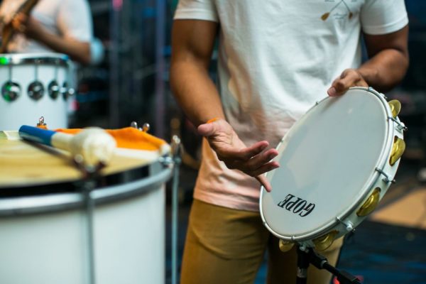 homem tocando pandeiro com um tambor de fundo