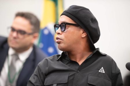 imagem colorida mostra ex-jogador de futebol ronaldinho gaúcho com roupas pretas e óculos escuros na cpi das ppiramides financeiras - Metrópoles