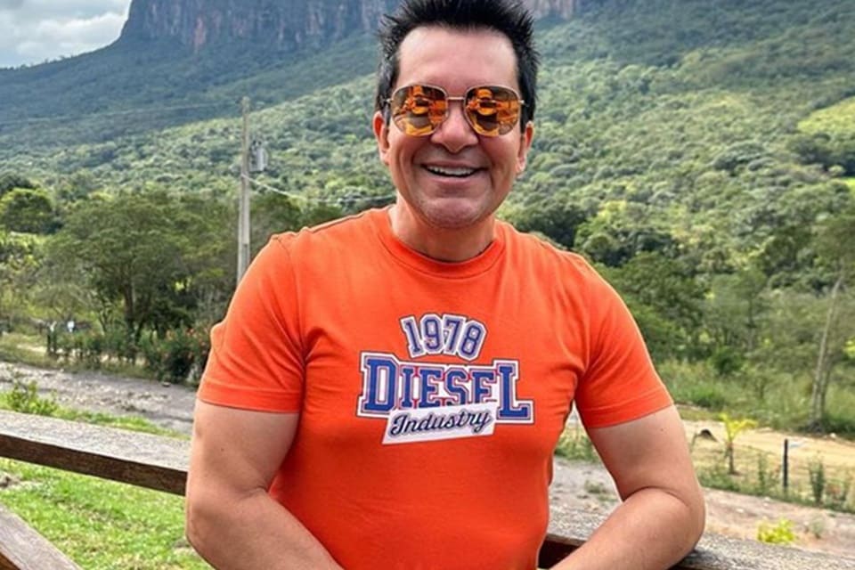 Regis Danese posa de blusa laranja - Metrópoles