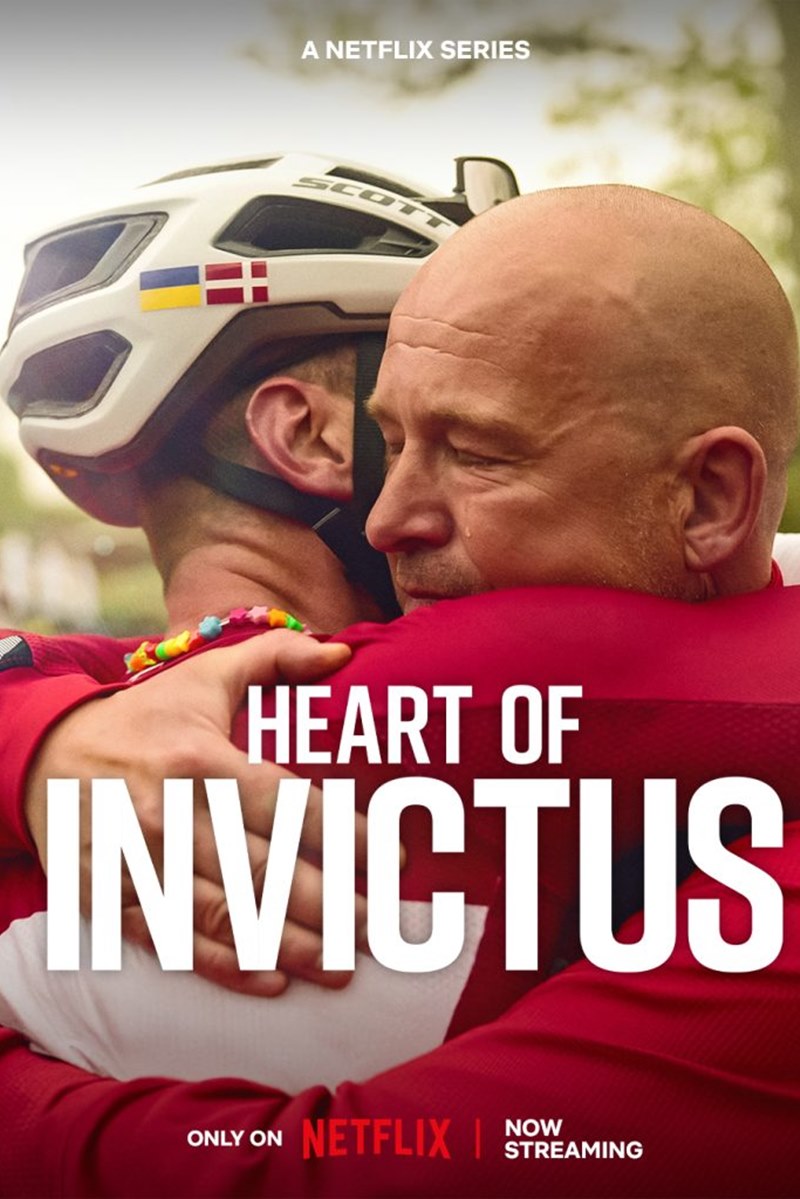 Foto colorida de pôster de filme em que mostra dois homens se abraçando, sendo um deles, com roupa de ciclista e outro calvo - Metrópoles
