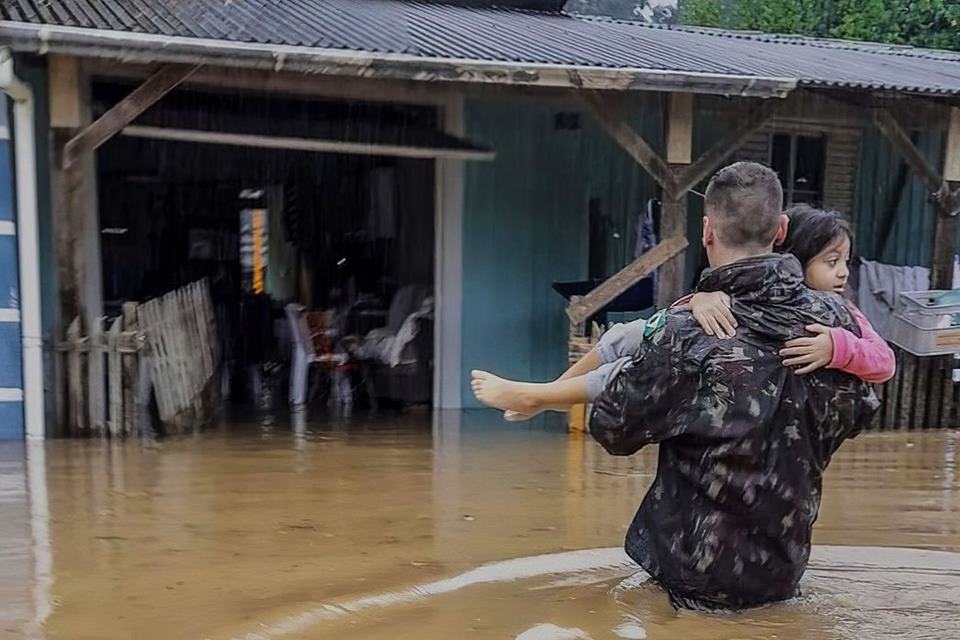 Eduardo Leite Ivete calamidade Foto colorida de criança sendo carregada por um homem durante o ciclone no Rio Grande do Sul chuvas - Metrópoles