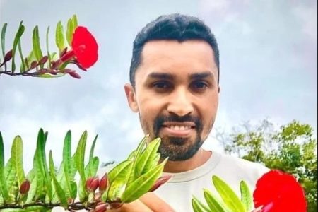 imagem de homem sorrindo, com flor e camisa branca