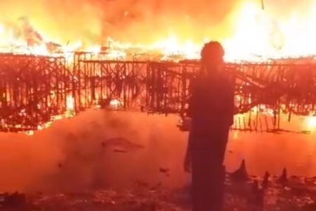 Foto colorida mostra casas pegando fogo em comunidade de Santos